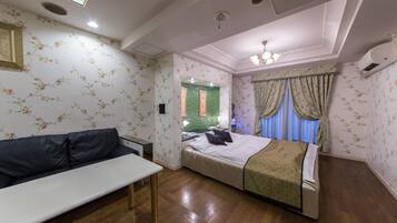 A bedroom with a bed, a bench, a desk, and a mirror.