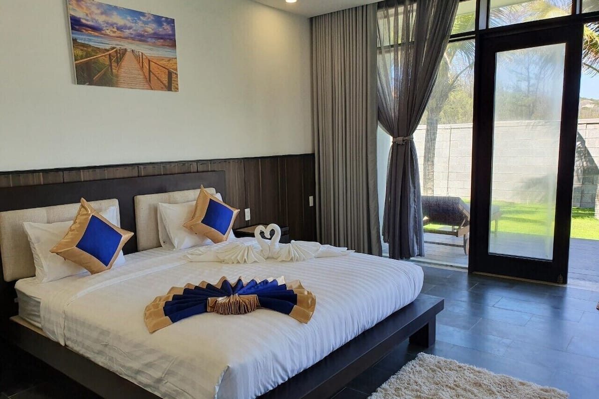 A large bed with a wooden headboard, white bedding, and decorative pillows.