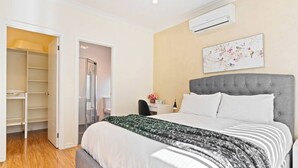 Ein Schlafzimmer mit Bett, Schreibtisch, Klimaanlage und Kleiderschrank.