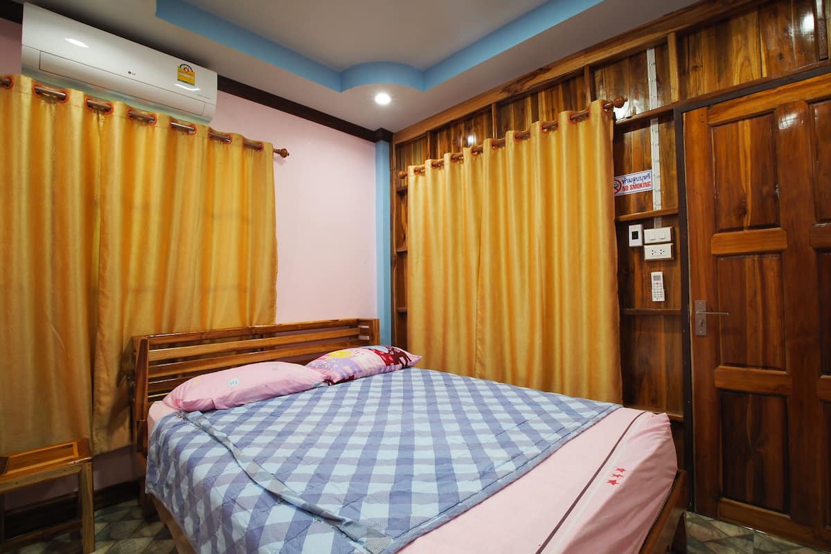 A bedroom with a wooden bed, checkered bedding, and curtains.