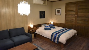 A bedroom with a bed, a sofa, a nightstand, a lamp, and a ceiling fan. - Hotel Keypoint - Adults Only (Kai)