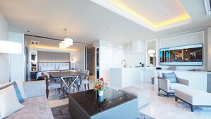 Une chambre d’hôtel moderne dotée d’un coin repas, d’une cuisine et d’un espace de vie avec une grande t élévision.