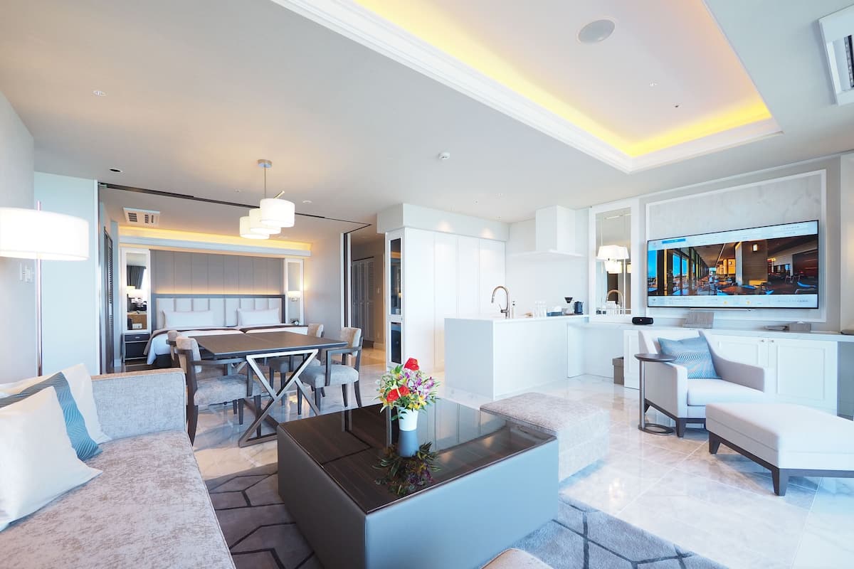 Une chambre d’hôtel moderne dotée d’un coin repas, d’une cuisine et d’un espace de vie avec une grande télévision.