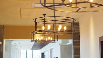 Un interno moderno con un lampadario multistrato in metallo con lampadine a vista, ampie finestre e una scala.