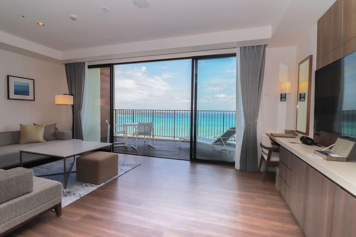 Une chambre d’hôtel moderne dotée d’un balcon, d’un canapé, d’une table à manger et d’un téléviseur.