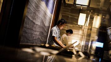 A man working at a counter in a modern hotel lobby with a stone wall and a large window.