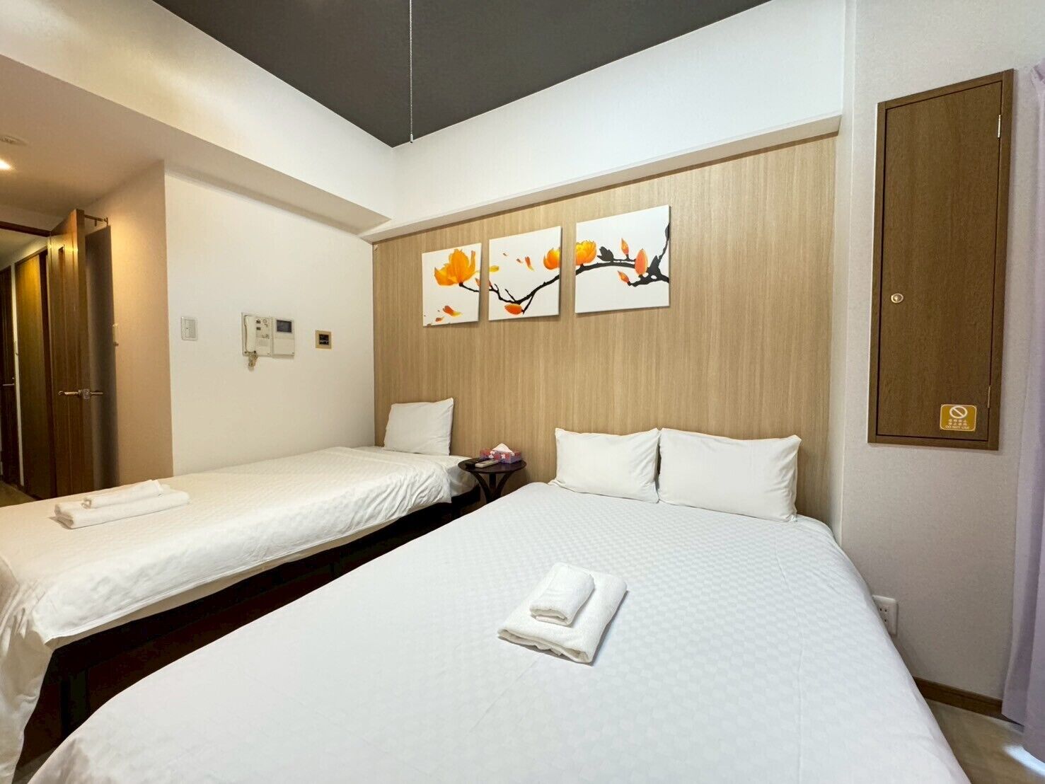 A hotel room with two beds, a wooden headboard, and wall-mounted artwork.