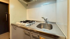 Una cocina compacta con estufa a gas, un lavamanos de acero inoxidable y una pequeña encimera.