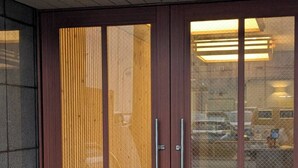 Una entrada de edificio moderna con un gran puerta de vidrio y un picaporte metálico.