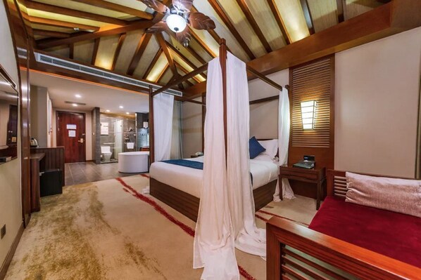 Un dormitorio con cama con dosel, techo de madera, baño y un escritorio pequeño.