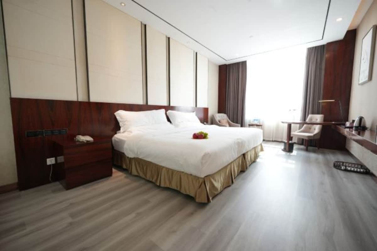 A modern hotel room with a large bed, a desk, and a chair.