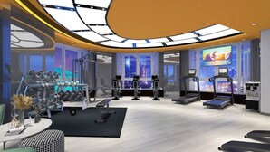 Une salle de sport moderne équipée de tapis de course, d’appareils de musculation et d’un grand écran de télévision.