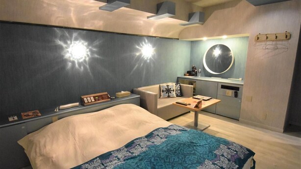 Een moderne slaapkamer met een bed, nachtkastje en een klein bureau met stoel.