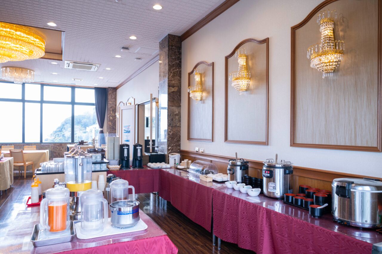 A buffet setup with various food stations, including hot and cold options, and a long table covered with a red tablecloth.