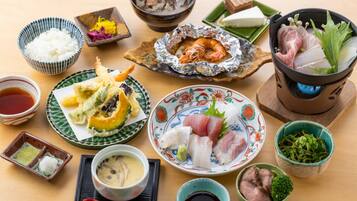 A variety of Japanese dishes including sushi, tempura, and a hot pot, arranged on a wooden table.