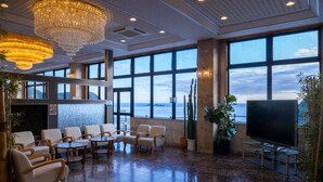Un vestíbulo amplio con un televisor grande, asientos cómodos y vista al mar.