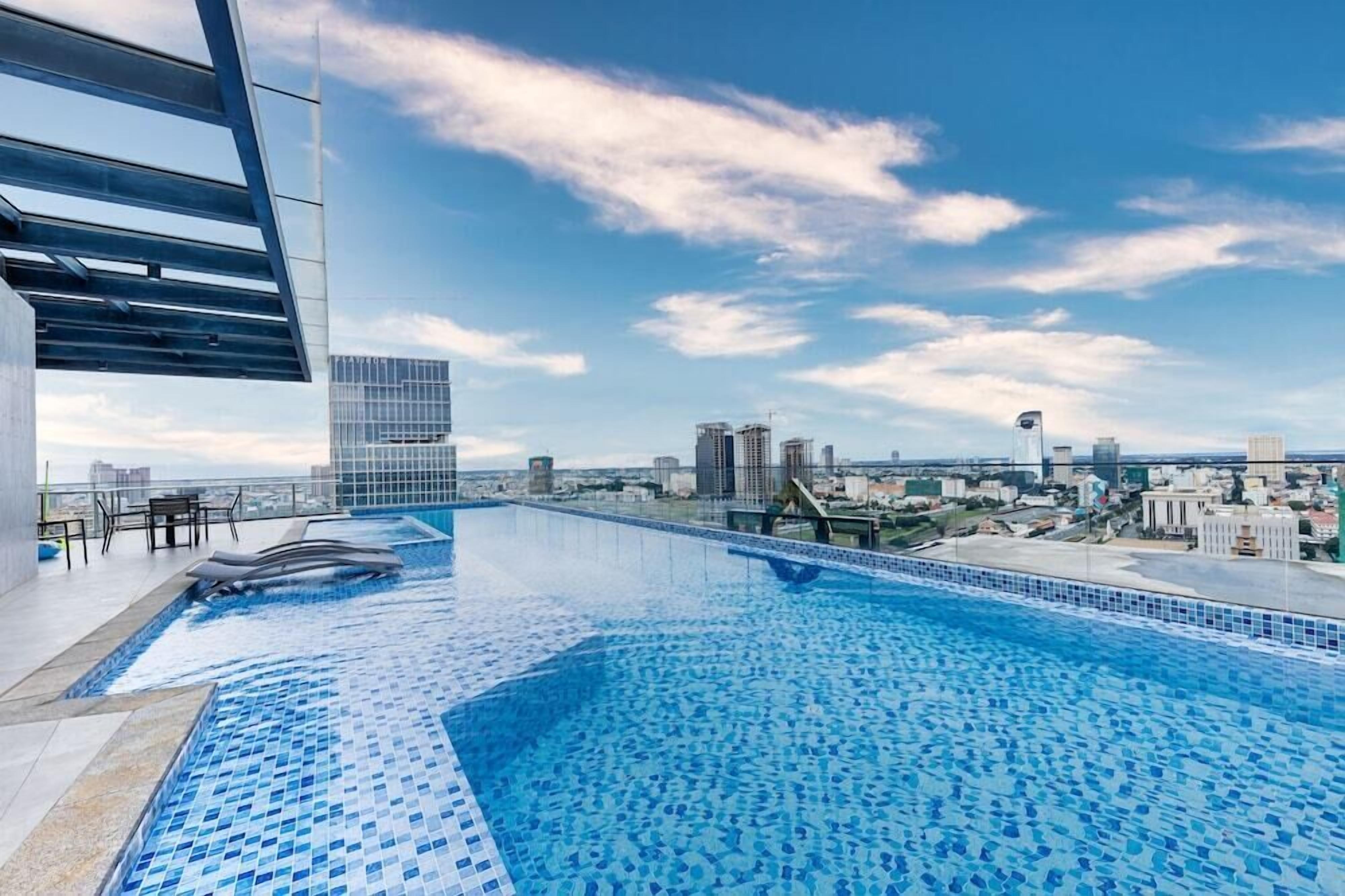A rooftop infinity pool with a city view, modern architecture, and a clear sky.
