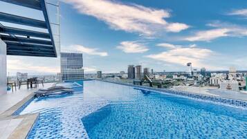 A rooftop infinity pool with a city view, modern architecture, and a clear sky.