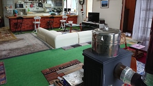 A compact living space with a kitchenette, a sofa, a dining area, and a small TV. - Fresh-Air-Inn (Teshikaga)