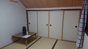 A room with tatami flooring, a wooden table with a vase and a skull ornament, and sliding doors. - Fresh-Air-Inn (Teshikaga)