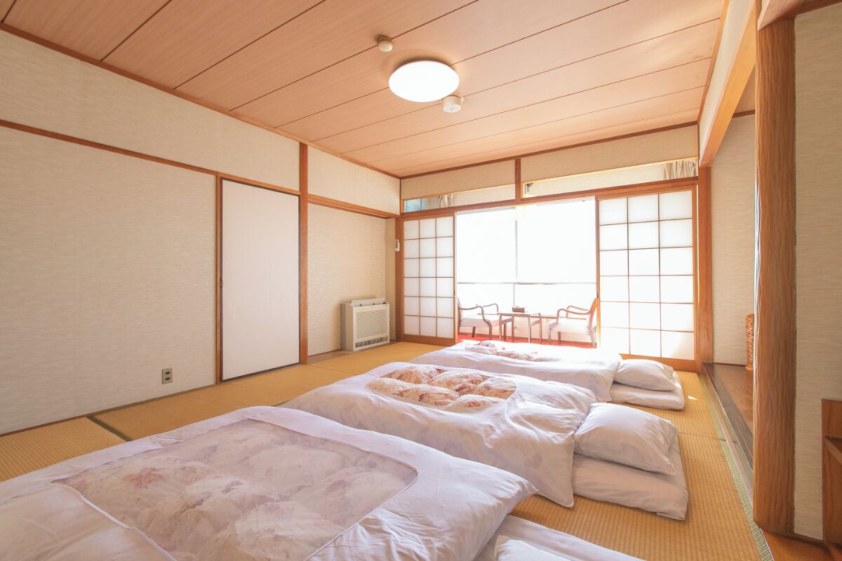 Una habitación japonesa tradicional con suelo de tatami, pantalla shoji y futón.