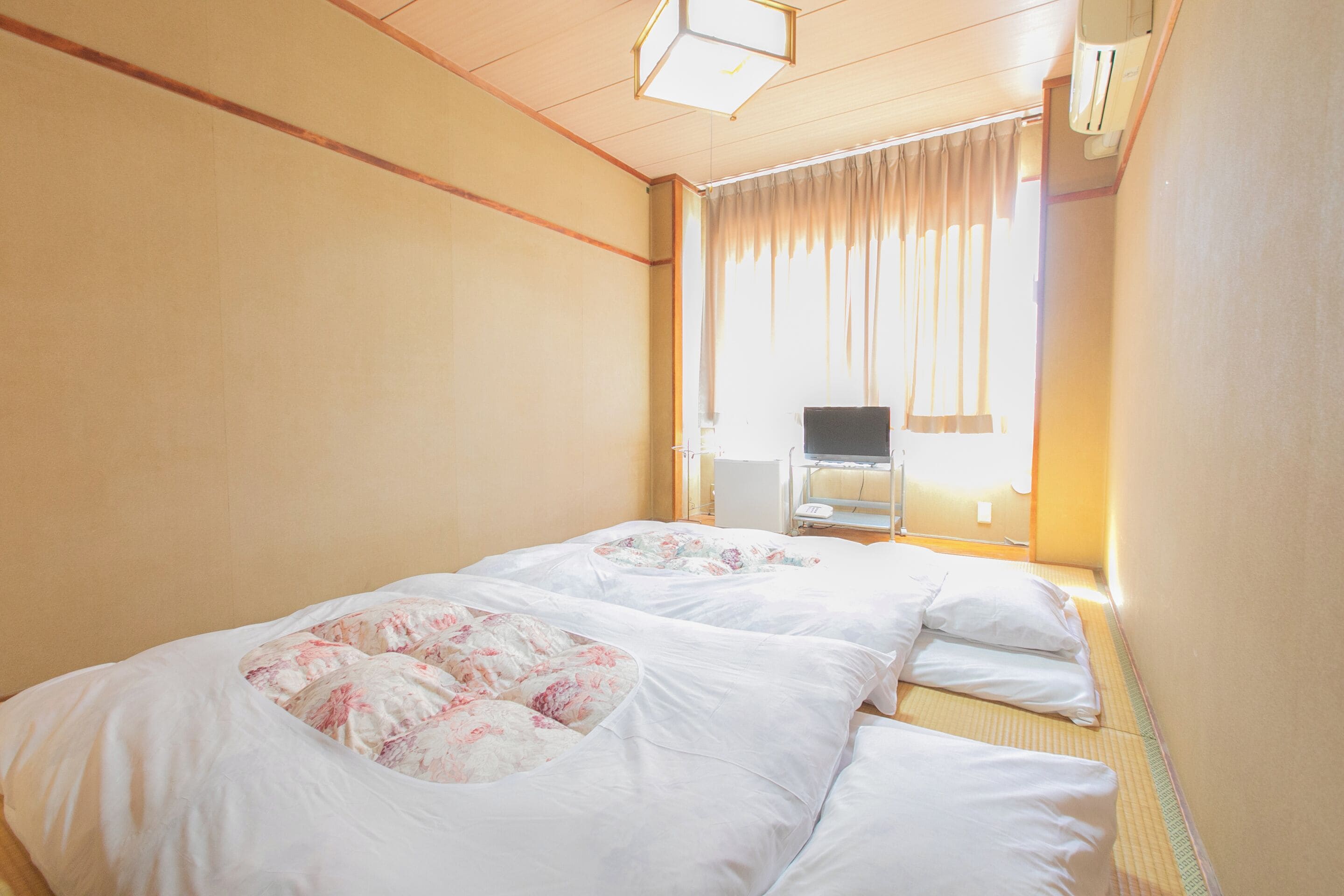 Una habitación de hotel con dos camas, una ventana con cortinas, una silla y una mesita de noche.