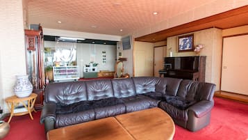 Una sala de estar con un sofá de cuero marrón, una mesa de centro de madera y un televisor.