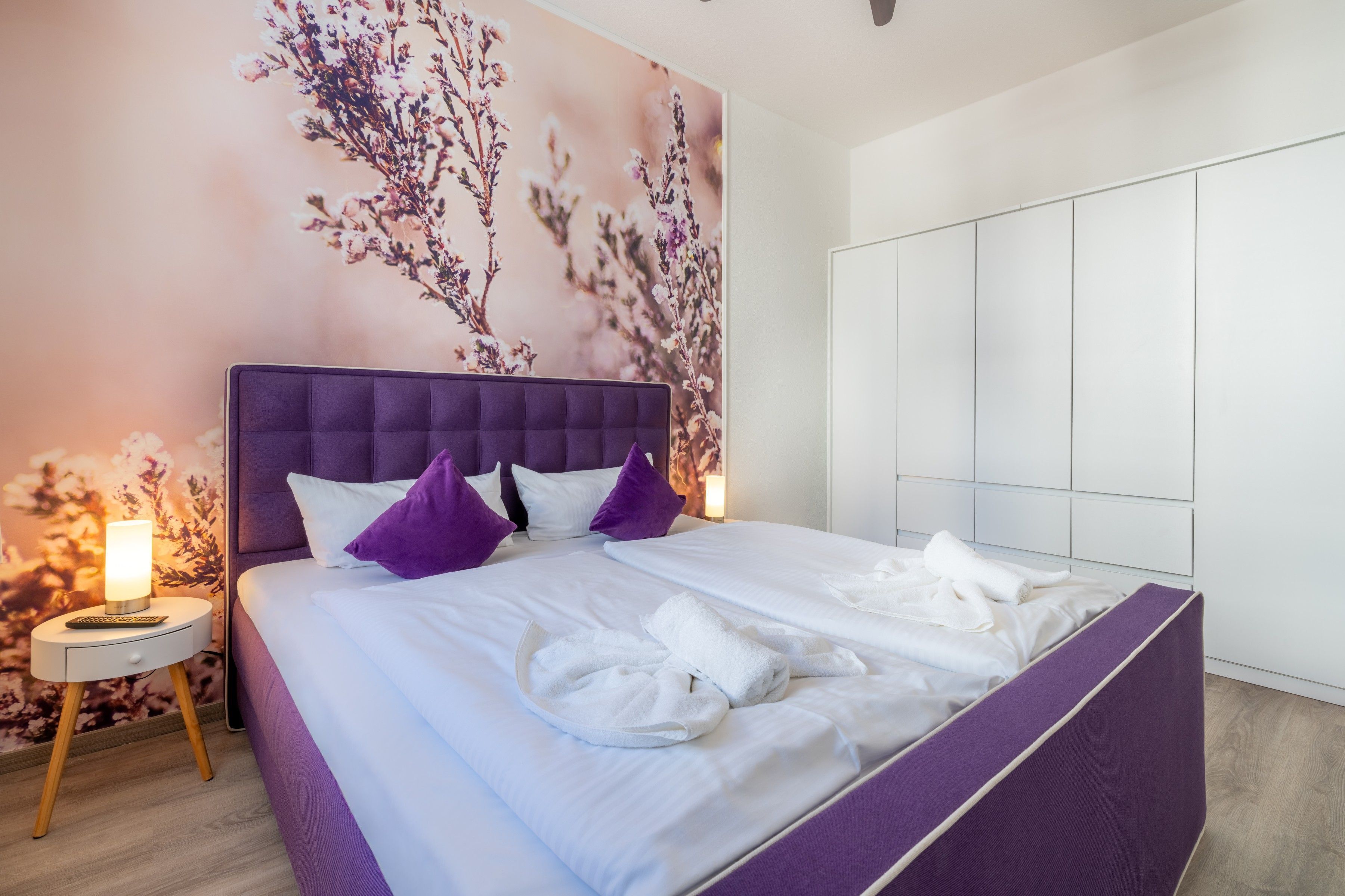 Una moderna camera d'albergo con un letto grande, un comodino e un armadio a muro.
