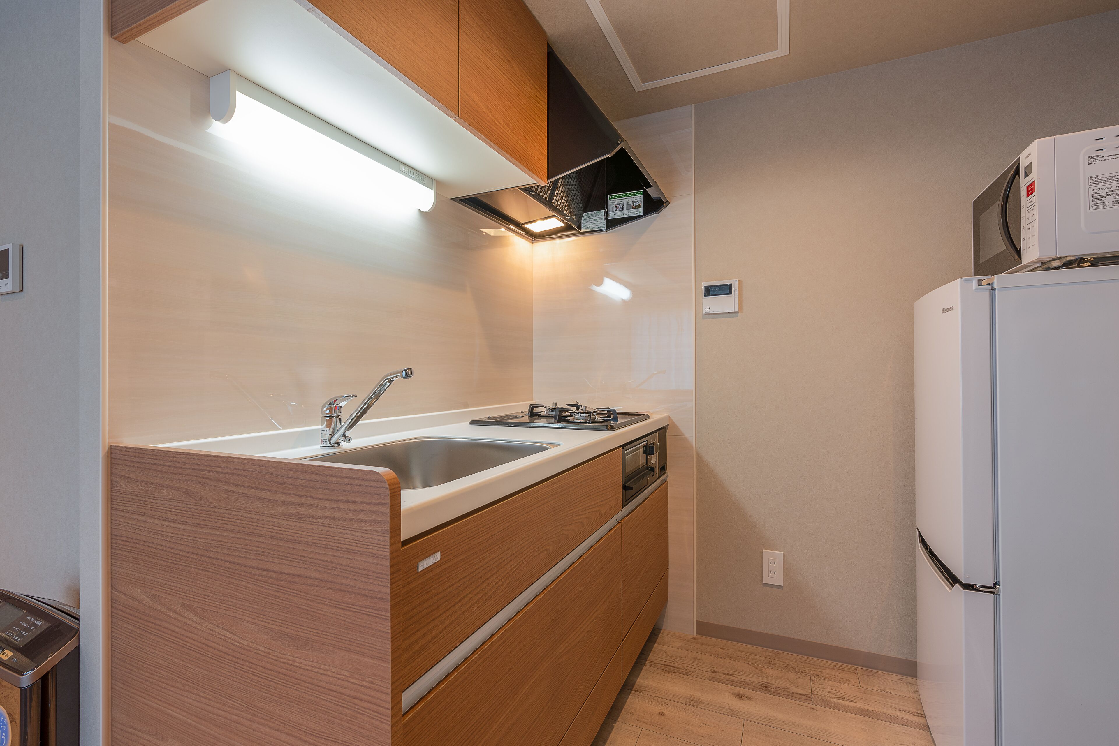 A modern kitchen with wooden cabinets, a stainless steel sink, and a built-in microwave.