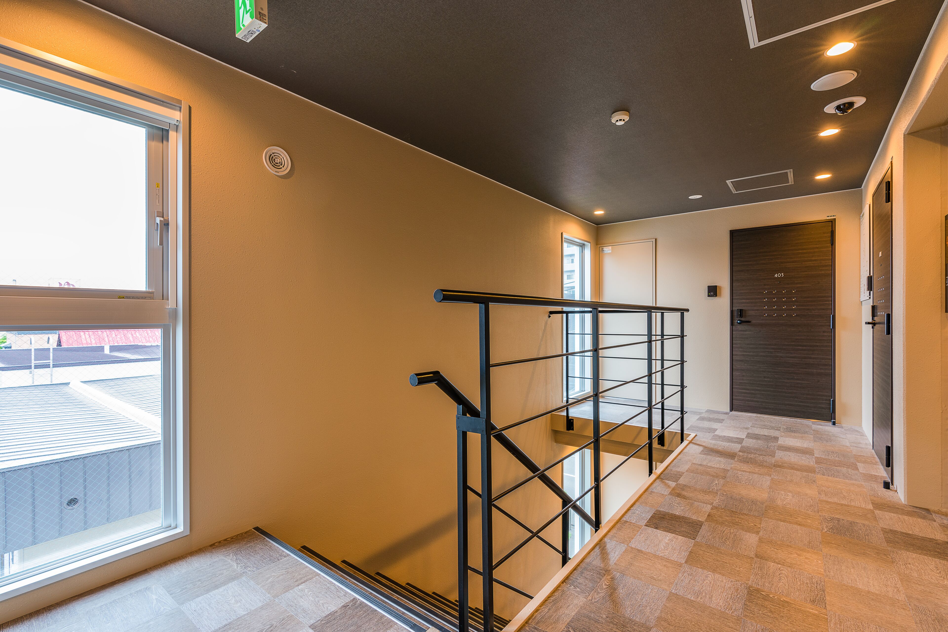 A modern interior with a staircase, a large window, and a door with a number.