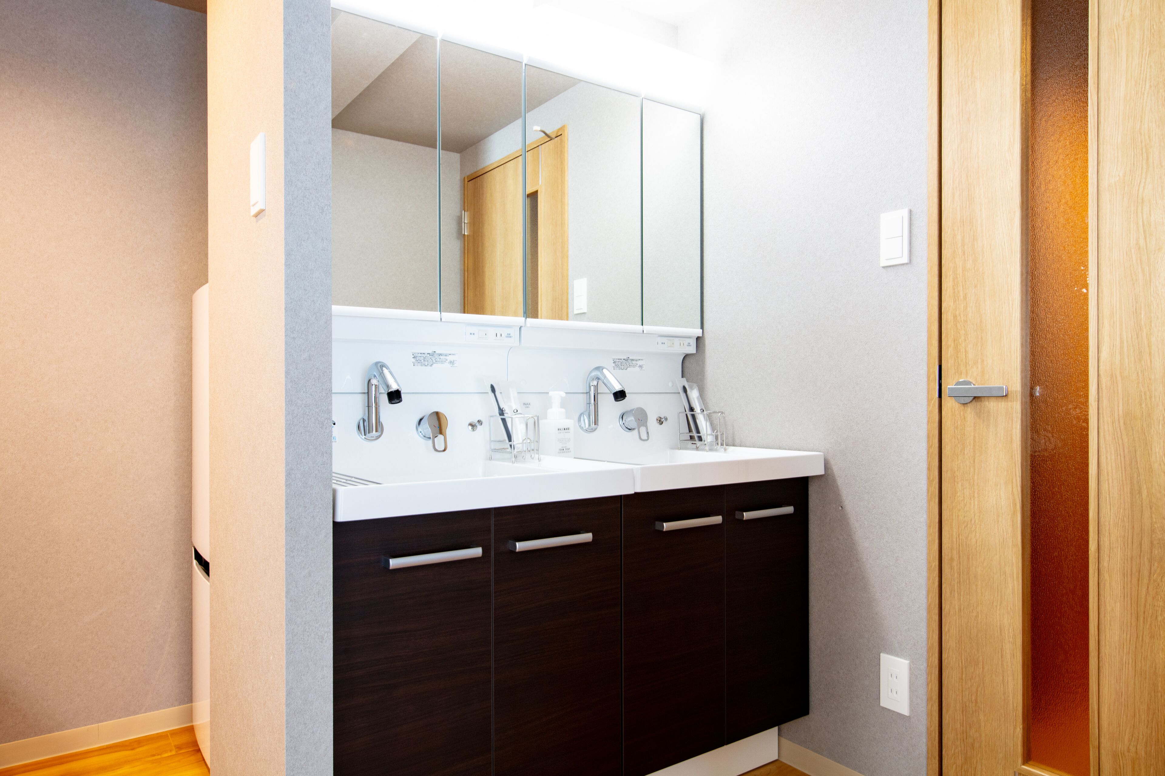 Un baño moderno con lavamanos doble, armarios de madera oscura y un espejo grande sobre el lavamanos.