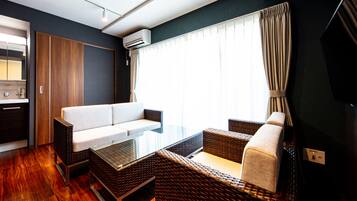 A modern room with a glass table, wicker furniture, a white sofa, and a large window with curtains.