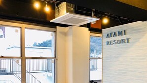 A room with a desk, chairs, a large window, and a wall with the text "ATAMI RESORT". - bnb Atami Resort - Hostel (Atami)