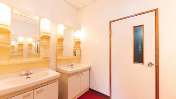 A hotel bathroom with two sinks, mirrors, and a door with a frosted glass panel.