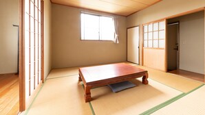 A traditional Japanese room with tatami flooring, a wooden table, sliding doors, and a window with curtains. - Tabist Watanabe Chiba Ichinomiya (Ichinomiya)