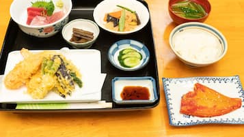 A tray with various Japanese dishes including sushi, tempura, and rice.