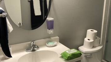 Ein Badezimmer mit rundem Spiegel, Waschbecken, Toilette und Handtuchhalter.