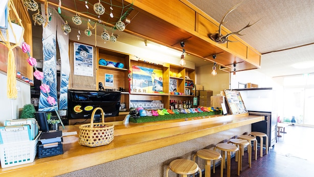 Un espace bar avec des tabourets en bois, un comptoir où sont exposés divers articles et des étagères ornées de décorations.