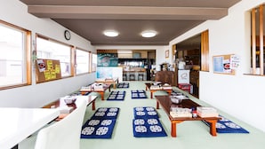 Une pièce de style japonais traditionnel, avec des tatamis, des meubles en bois et une vue sur la cuisine en arrière-plan.