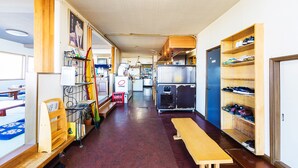 Un couloir étroit avec un banc en bois, un porte-chaussures et un réfrigérateur.