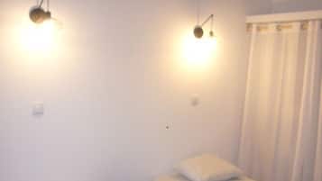 A room with two single beds, a small round table, and two wall-mounted light fixtures.