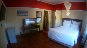 Una habitación de hotel con cama, escritorio, televisor y espejo.