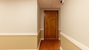 Un couloir avec une porte en bois, des murs de couleur beige et un plancher en bois.