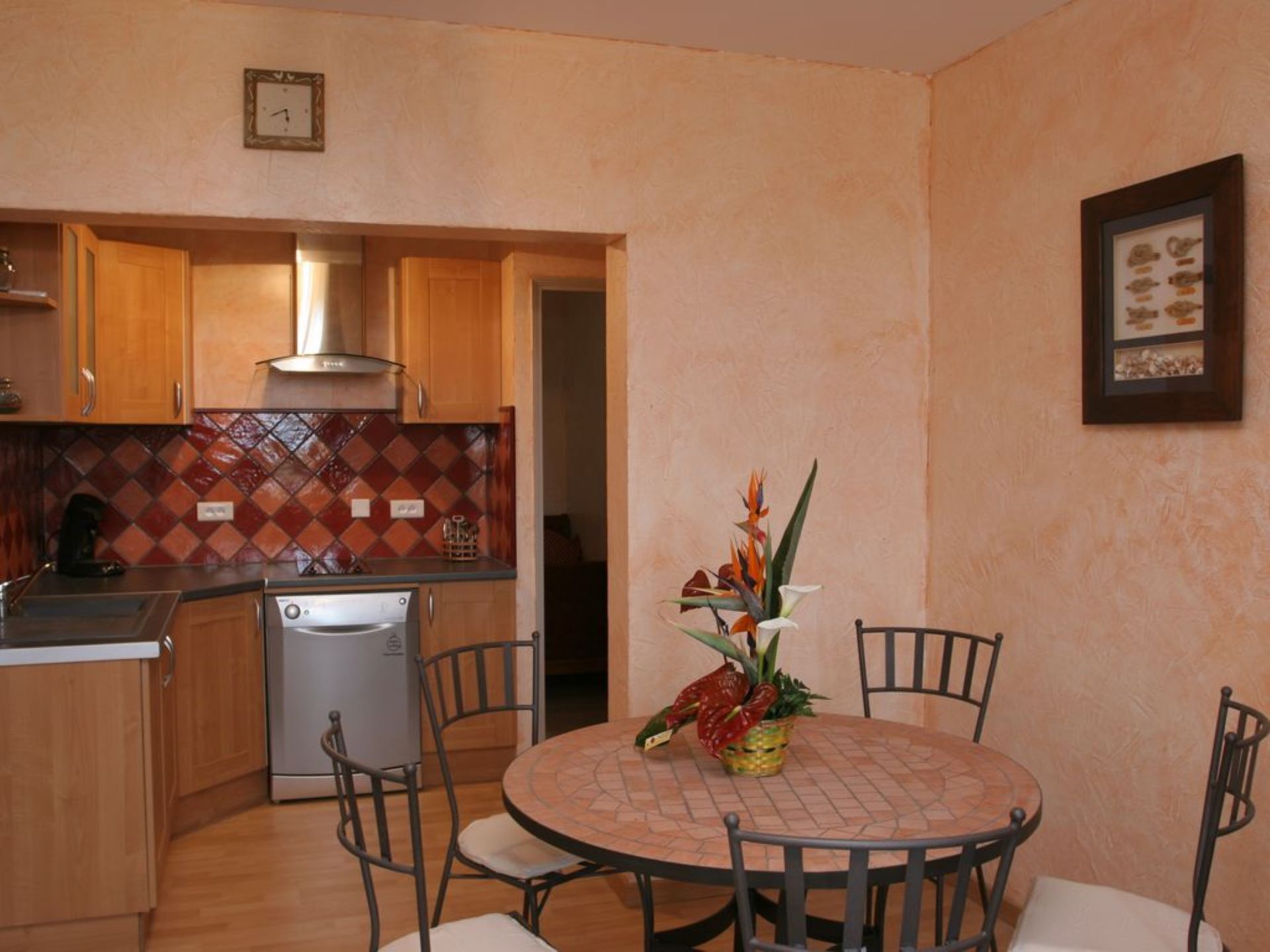 A compact kitchen with wooden cabinets, a stainless steel refrigerator, and a tiled backsplash.
