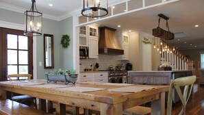 Une cuisine spacieuse dotée de meubles en bois, d’un grand îlot central et de luminaires suspendus.