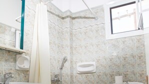 A bathroom with a shower, toilet, sink, and a window. - Louiza Hotel (Paros)