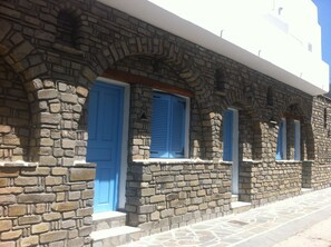 Ein Steinhaus mit blauen Türen und Fensterläden, das traditionelle Architektur mit Rundbogenfenstern und einer Steinfassade zeigt.