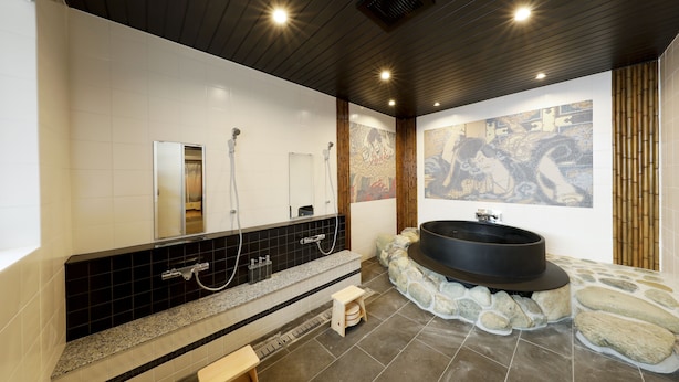 A modern bathroom with a large bathtub, a shower area, and a stone mosaic wall. - Kamanoyado - Tennoji (Osaka)