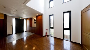 A spacious hallway with wooden flooring, large windows, and a fire extinguisher near the entrance. - Kamanoyado - Tennoji (Osaka)