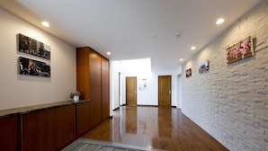 A hallway with wooden flooring, a reception desk, and artwork on the walls. - Kamanoyado - Tennoji (Osaka)